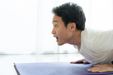 Funny tired face of Asian young man laying down on the floor. Man tired from hard workout.