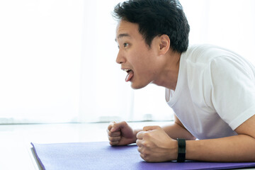 Funny tired face of Asian young man laying down on the floor. Man tired from hard workout.