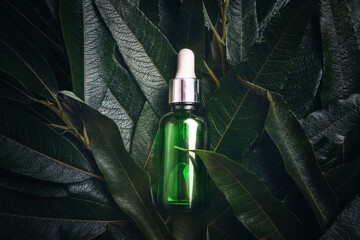 Green bottle with a dropper on a bio background made of natural leaves with cosmetics serum,...