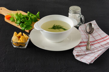 Homemade chicken bouillon or broth. healthy dinner. black concrete background.