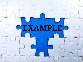 Selective focus.Word EXAMPLE with jigsaw puzzle on blue background.Business concept.