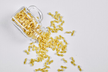 Top view of raw pasta inside the a glass jar on grey background