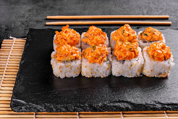 baked sushi with salmon, avocado, red caviar and cream cheese isolated on black background. Delicious traditional Japanese food with sushi rolls. Hot sushi