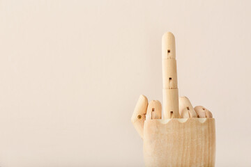 Wooden hand showing middle finger on light background, closeup