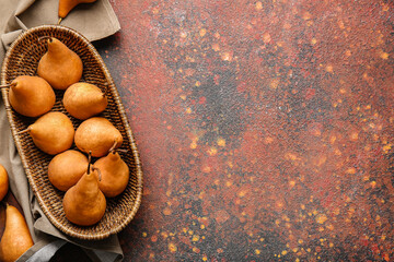 Basket with fresh ripe pears on grunge background