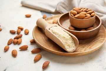 Scoop with almond flour and bowl of nuts on light background