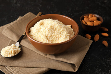 Spoon and bowl with almond flour on dark background