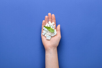 Female hand with chewing gums on color background