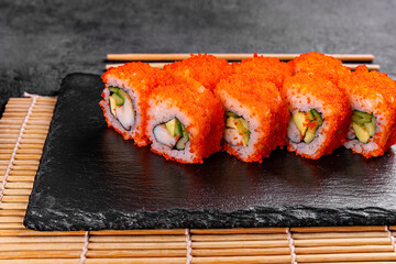 Golden dragon sushi roll with crab, salmon, cucumber, sesame seeds and cream cheese over black backgraund. Top view