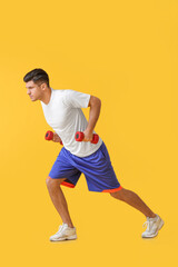 Fototapeta na wymiar Sporty young man training with dumbbells on color background