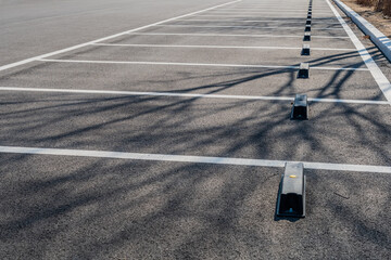 Row of empty parking spaces marked with white lines in paring lot of wilderness park. © aminkorea