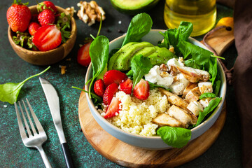 Healthy food, diet lunch menu concept, ketogenic diet and paleo diet. Couscous salad with strawberries, grilled chicken, avocado and feta cheese on a stone table.