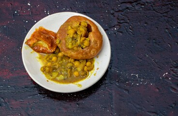 Indian Snack Kachori with Ghugni Curry and Mango Pickle in a Plate Isolated on Black Background with Copy Space for Texts Writing