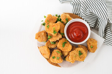 Homemade chicken nuggets with ketchup on a wooden board, top view