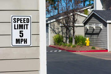 5 mph speed limit sign on garage in residential area. Blurred driveway in residential complex