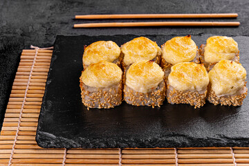 Baked roll with shrimp and masago caviar cap. Traditional sushi restaurant dish, menu item. National japanese cuisine appetizer. Delicious oriental snack, gourmet seafood on wooden platter closeup
