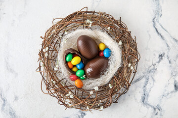 Nest with chocolate Easter eggs on light background