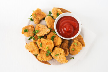 Homemade chicken nuggets with ketchup on a wooden board