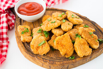 Homemade chicken nuggets with ketchup on a wooden board