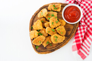 Homemade chicken nuggets with ketchup on a wooden board, close up