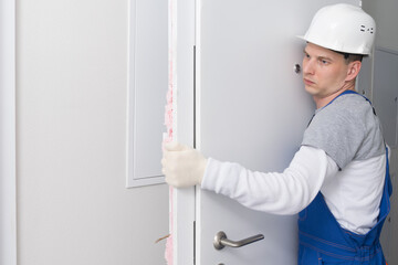 the master on installation of doors, takes out the old door on a garbage can