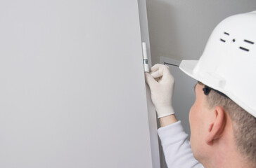 male construction worker, puts caps on the hinges of the front door to protect against dust