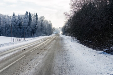 Obraz premium Winter road in snowy forest on a cold day.