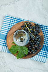 A cluster of black grapes with leaf and a glass of wine on white background