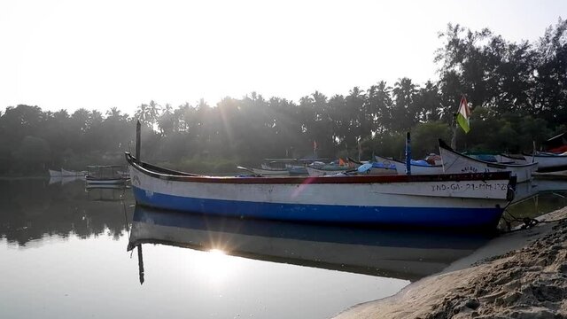 Sunlight Reflects Through Calm Water With Fishing Boat Dock During Sunrise In Palolem Beach, South Goa, India. - Static Shot