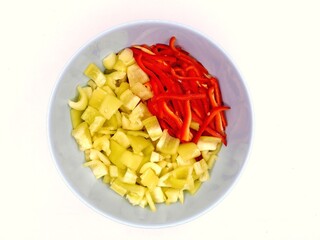 Top view photo of a bowl filled with sliced green and red bell peppers.