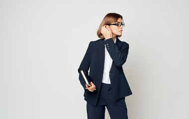 Business woman in a blue jacket and a white shirt with glasses on her face and a book in her hands