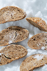 Two rows of frozen grey bread slices in a grinded ice. top view. Resting flat, arranged in two rows.