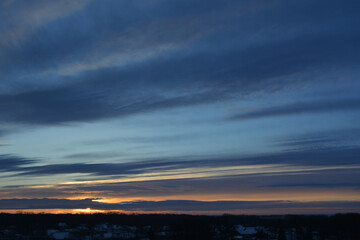 Landscape with sunset at winter. Dark blue striped clouds on the sky