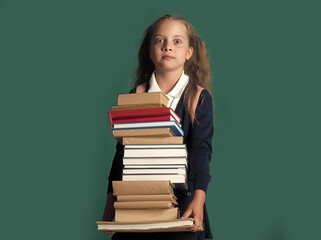 Funny Kid. Back to school and homework concept. Schoolgirl with shocked face holds huge pile of books.