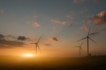 Obraz premium Silhouette of wind turbines. Beautiful view of wind generators in the mountain hill at sunset.