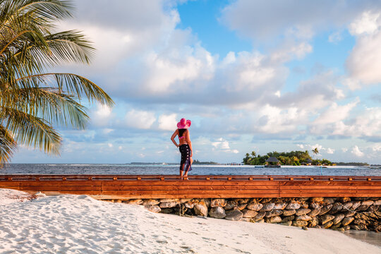 Woman walking on a beach at sunset, Maldives