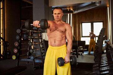 Naklejka premium Muscular man doing various exercises with a pair of dumbbells