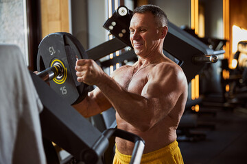 Positive male athlete adjusting a weight for a barbell
