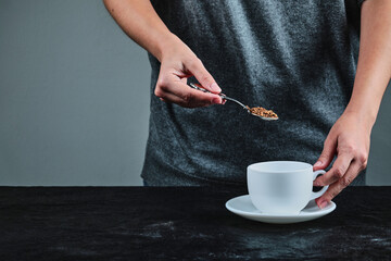 Hand holding spoon full of coffee on the dark background
