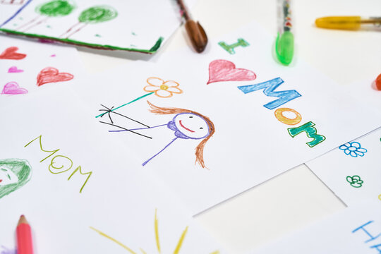 The best homemade gifts for Mom from kids. Top view of beautiful colorful child drawings for mothers day on white background