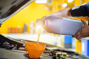 Close up image of pouring oil to car engine.