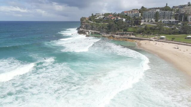 Tourists Walk At Bronte Beach In Summer - Surfers On Surfboard Ride And Enjoying Ocean Waves - NSW, Australia. - aerial