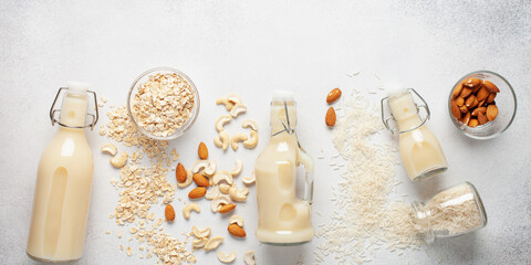Dairy free alternative nut milk in glass bottles on a gray background. Healthy vegan food concept.