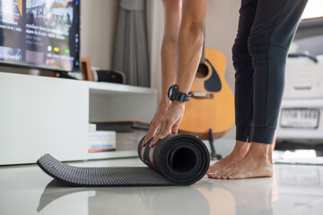 Young man practicing yoga and meditating at home. He preparing material for practice yoga class via online channels with expert teachers. He was happy to do yoga at home during his quarantine period.