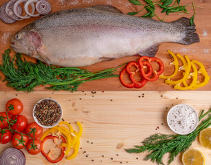 fresh carcass of fish lying on a natural wooden board, served with fresh vegetables, herbs and spices. view from above. place for your inscription