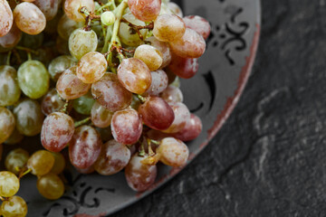 A bunch of mixed grapes on a ceramic plate, close up