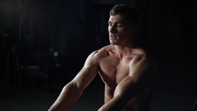 Athletic man in the Gym lifting blocks on rowing machine, training on block device and gym equipment, 4k Slow Motion.