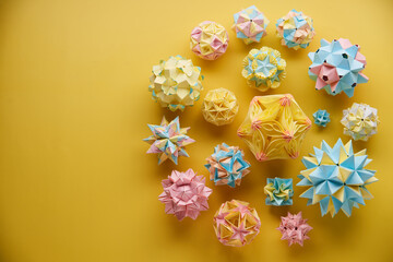 Set of multicolor handmade modular origami balls or Kusudama Isolated on yellow background. Visual...