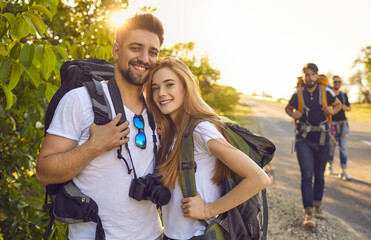 Young couple of tourists with backpacks with friends on a trip in nature.