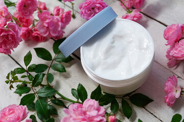 Fototapeta na wymiar natural facial cream cosmetic, fresh as spring flowers with green leaves on white wooden background